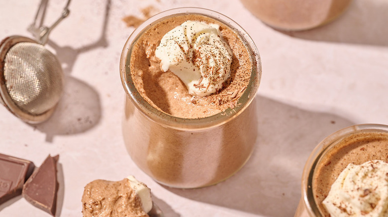 Mocha mousse in glass jar, topped with whipped cream and garnished with cocoa and chocolate