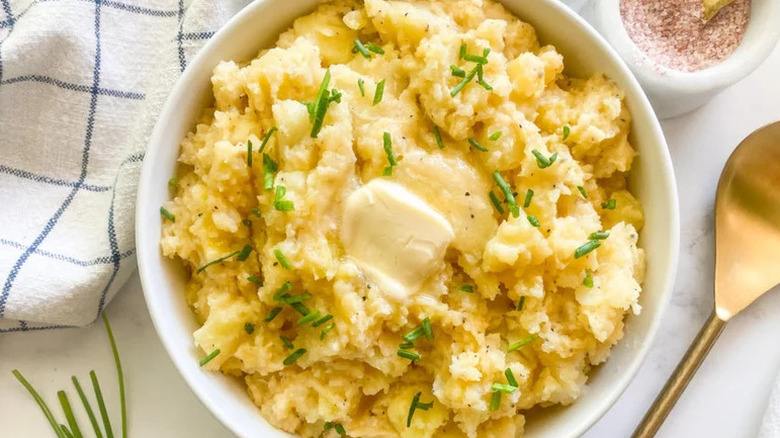 Creamy Instant Pot Mashed Potatoes with butter and herbs in white bowl