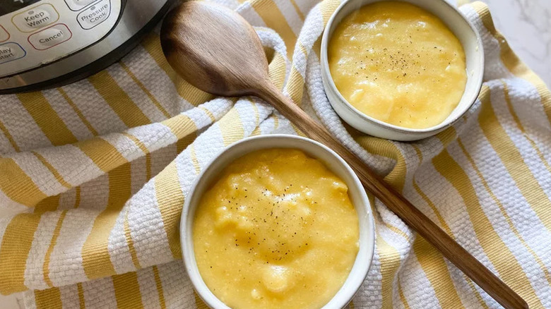 Creamy Instant Pot Polenta in two white bowls with wooden spoon