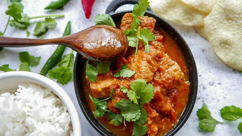 Instant Pot Chicken Madras in black bowl with wooden spoon