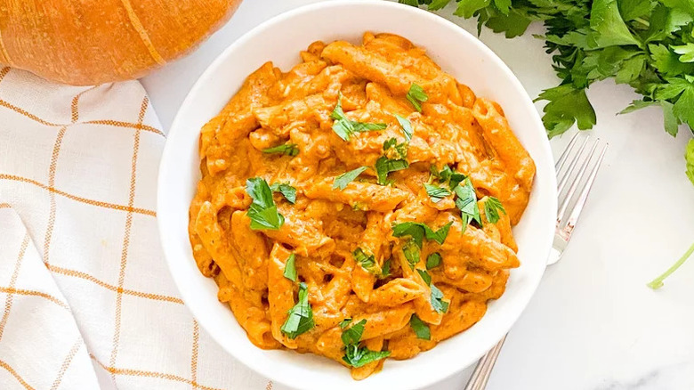 Instant Pot Pumpkin Pasta with torn herbs in white bowl