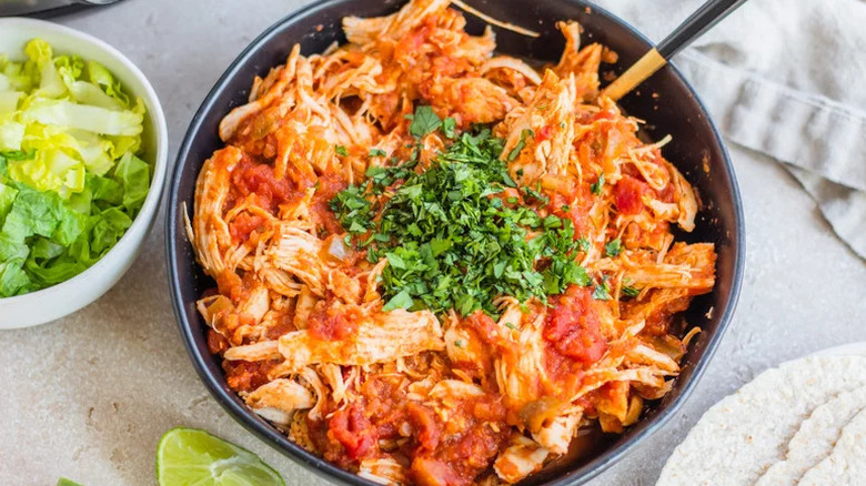 Instant Pot Salsa Chicken with herbs in large black bowl