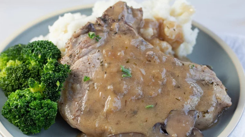 Instant Pot Smothered Pork Chops on grey plate with mashed potatoes and broccoli