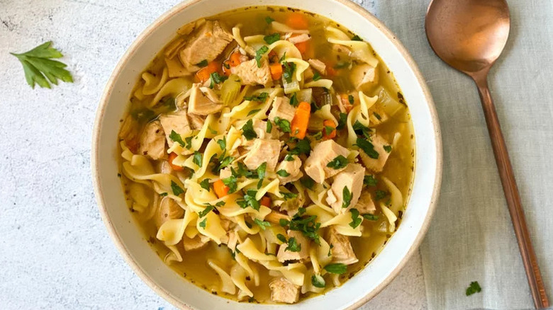 Instant Pot Turkey Soup in white bowl with copper spoon