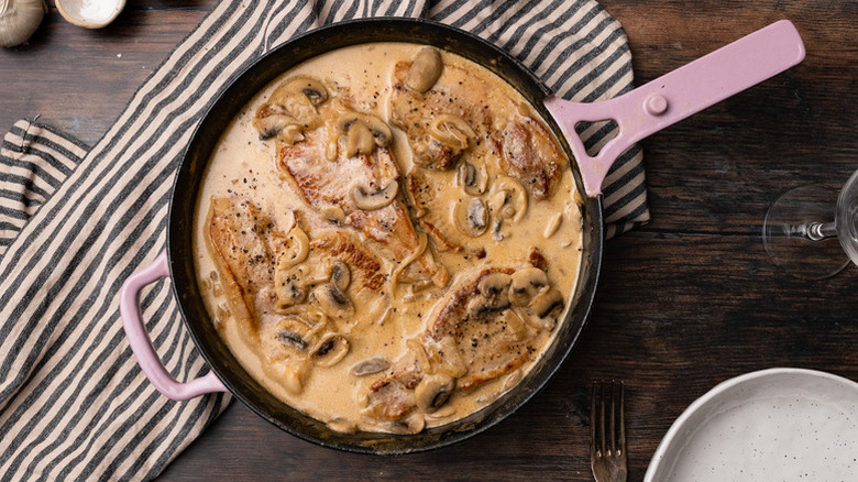 Pork chops in skillet with creamy sauce and mushrooms