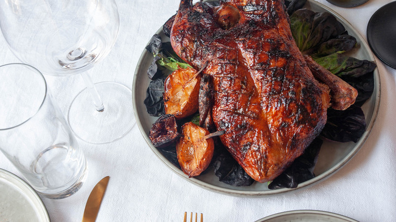 Crispy whole roasted duck on plate with pears and figs