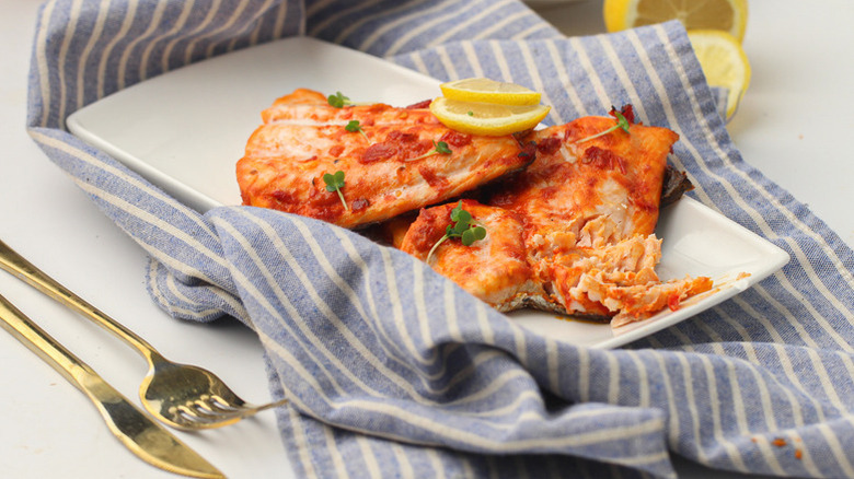 Harissa baked salmon on white serving plate with lemon slices