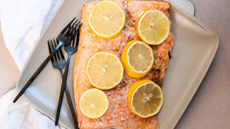 Baked salmon on plate, topped with lemon rounds