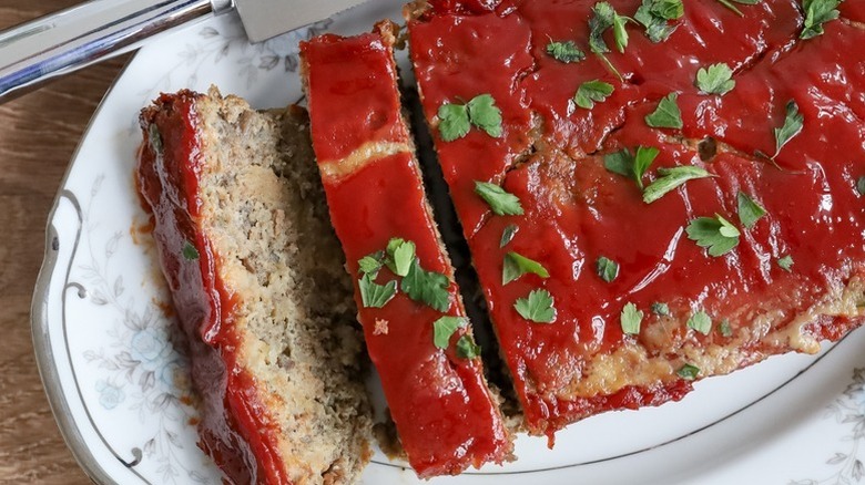 Glazed, sliced turkey meatloaf on plate, topped with fresh parsley