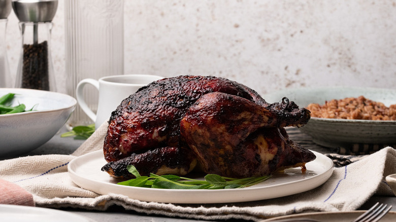 Whole roast chicken with blackberry glaze, served on white plate