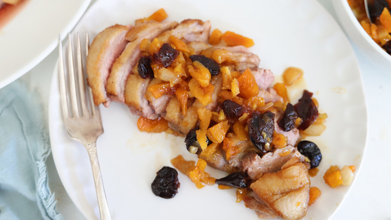 Sliced duck breast on plate, topped with apricot chutney