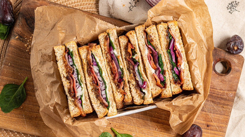 Sliced bacon, date, and goat cheese paninis in parchment-lined dish