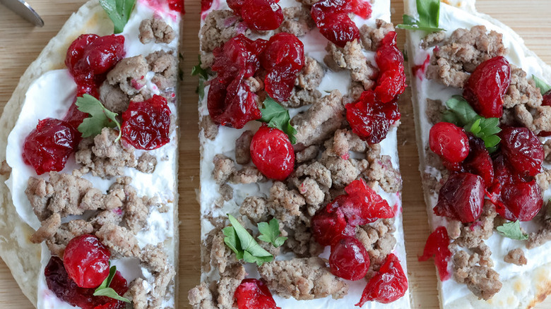 Sliced flatbread topped with ground turkey and cranberries