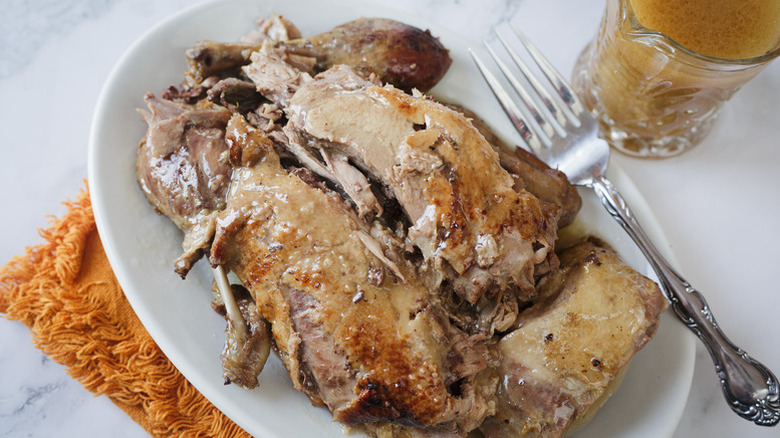 Slow-cooked duck on serving plate with fork