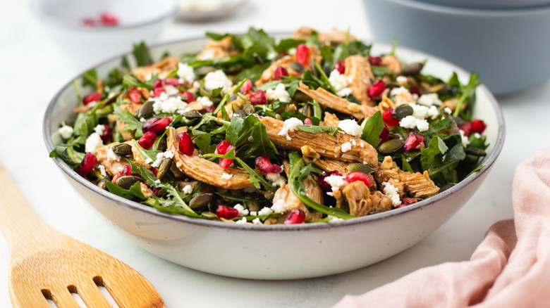 Arugula, pomegranate, feta, and chicken salad in bowl