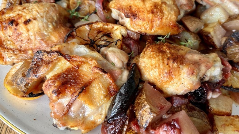 Close up of roasted chicken and plums on plate