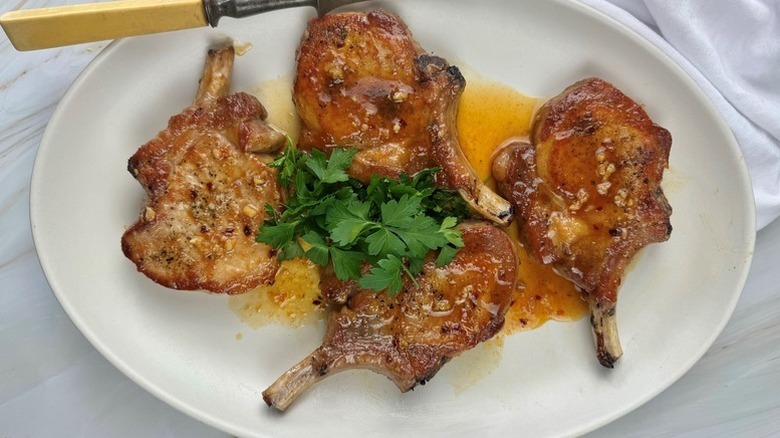 Apricot-glazed pork chops on plate, topped with fresh parsley