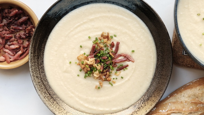 Bowl of cauliflower potato soup topped with bacon bits and chives
