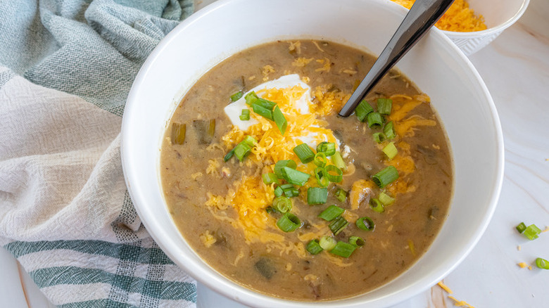 Bowl of potato leek soup, topped with green onions, sour cream