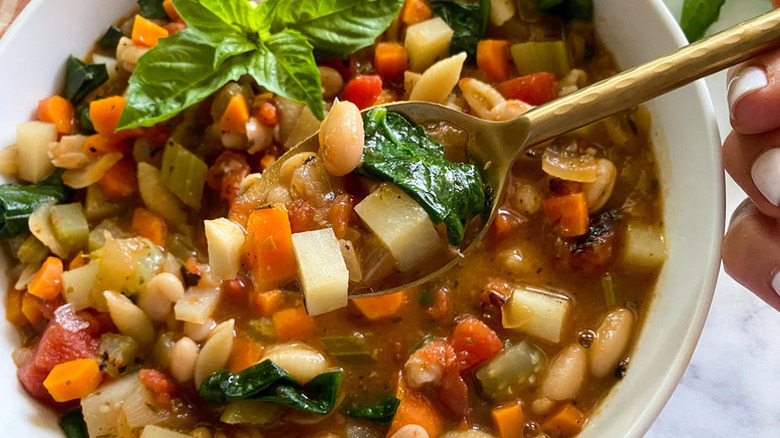 Spooning minestrone soup from bowl