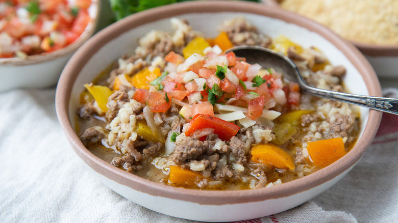 Bowl of ground beef and vegetable soup, topped with pico de gallo