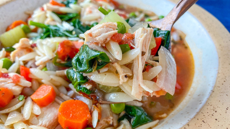 Spooning turkey vegetable soup from bowl