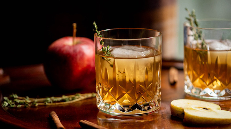 Apple cider old fashioned cocktail in glass with ice and sprig of thyme