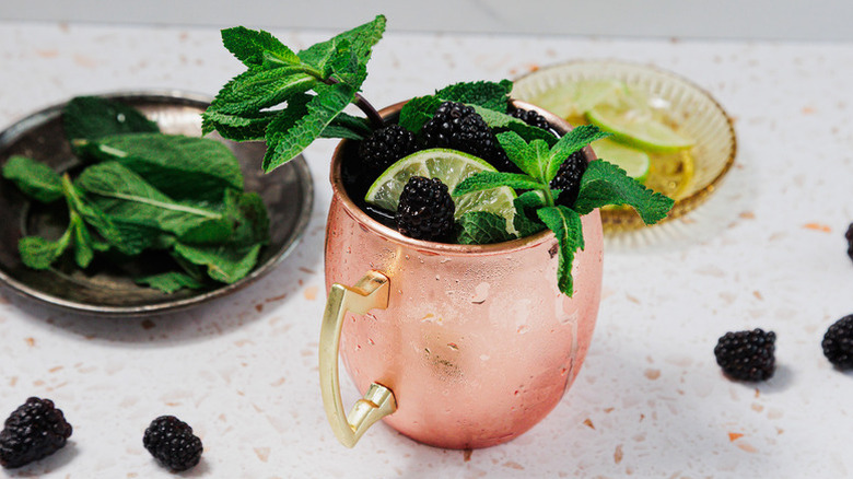 Blackberry Kentucky mule cocktail in copper mug, garnished with fresh mint, lime, and blackberries