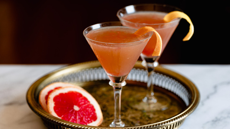 Two brow Derby cocktails in martini glasses,  each garnished with a grapefruit twist