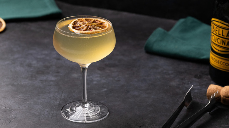 French 95 cocktail in long-stemmed glass, garnished with dried orange slice