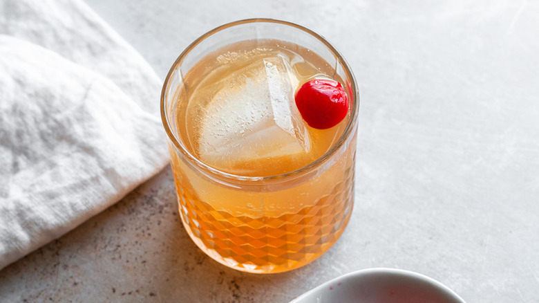 Amaretto sour cocktail in glass with ice and maraschino cherry