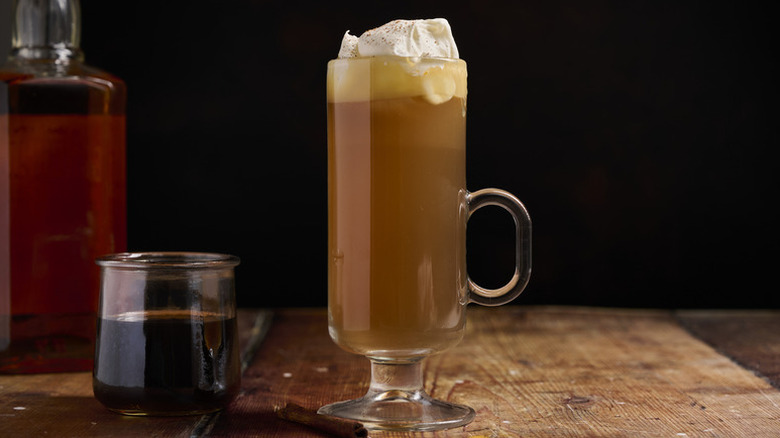 Hot whiskey cocktail in tall handled glass, topped with whipped cream