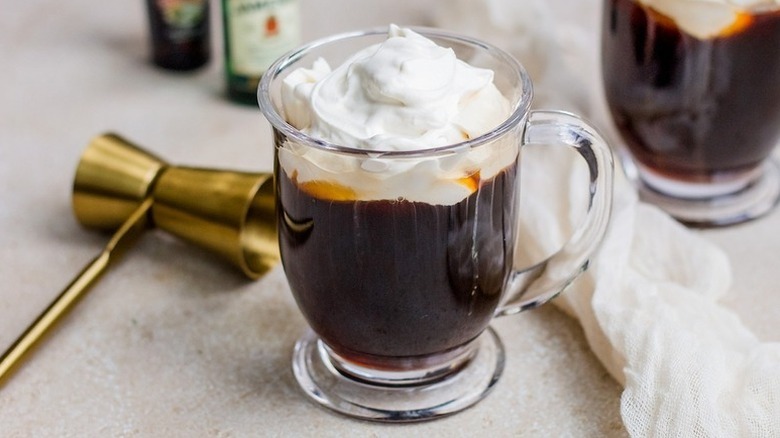 Irish coffee cocktail in glass mug, topped with whipped cream
