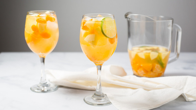Citrusy white wine sangria served from pitcher into two glasses