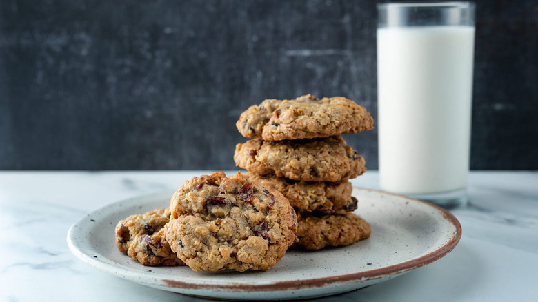 Stack of cranberry orange oatmeal cookies on plate, next to glass of milk
