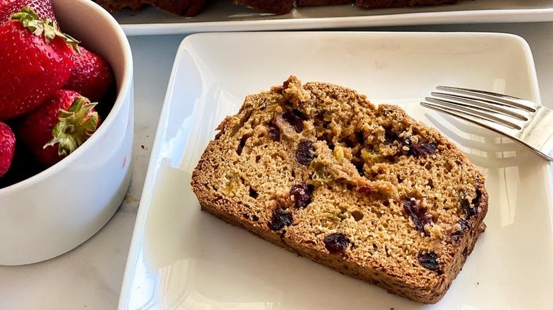 Slice of fruit bread on white plate with fork