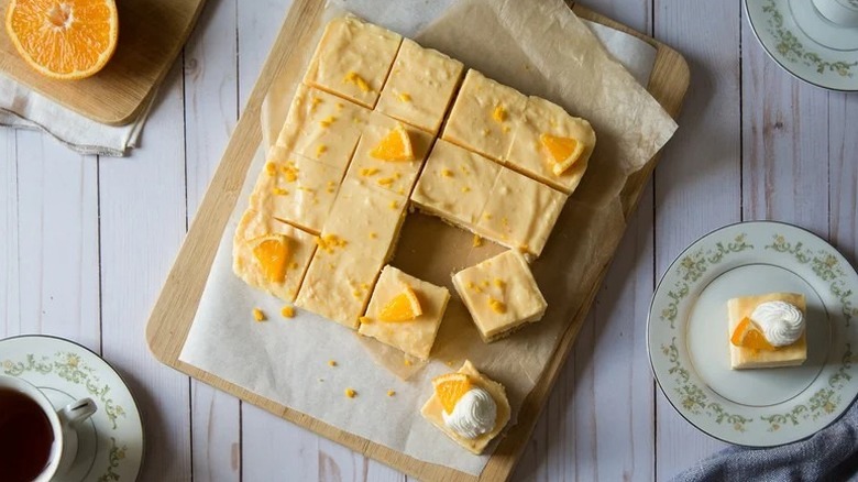 Slices of creamy orange no-bake dessert on parchment-lined wooden board