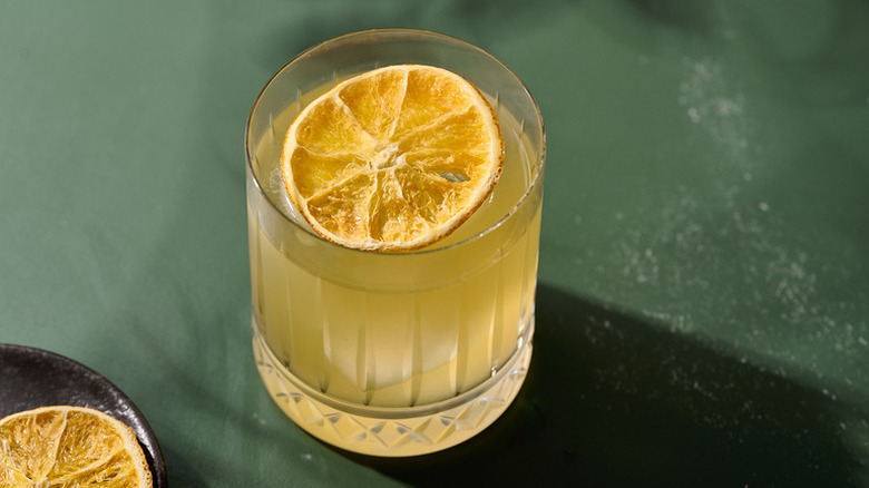 Orange margarita cocktail in rocks glass, garnished with dried orange slice