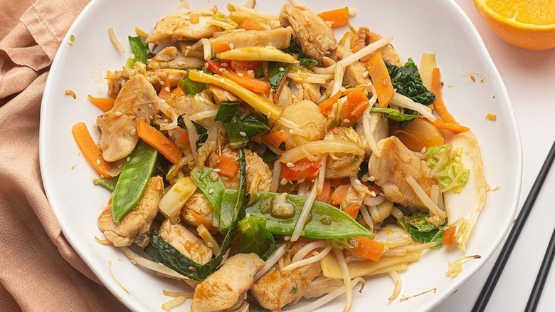 Orange chicken vegetable stir fry on white plate