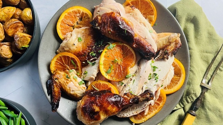 Roasted chicken on plate with orange slices