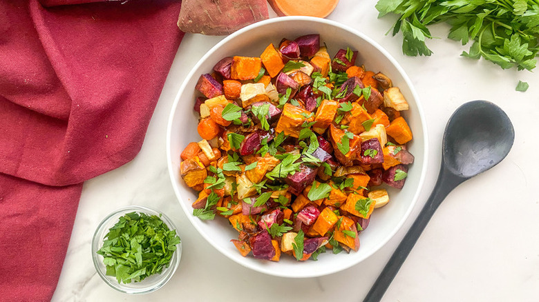 Roasted root vegetables in bowl with chopped parsley garnish