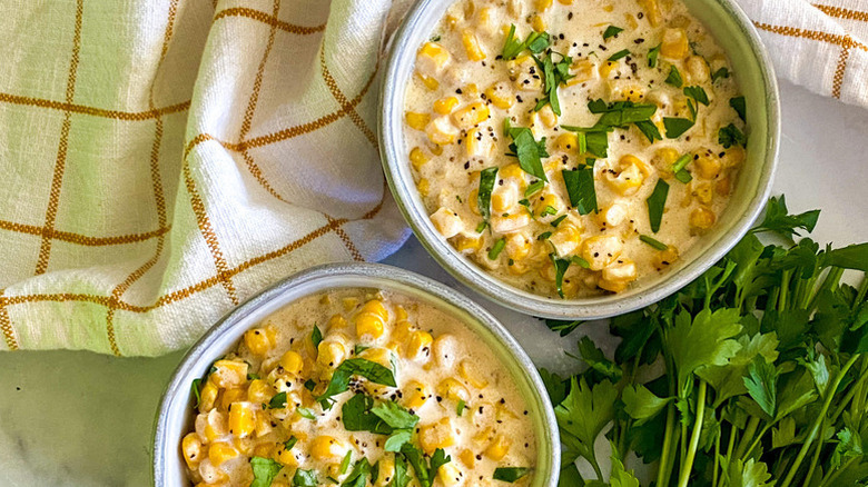 Two bowls of creamed corn, garnished with parsley
