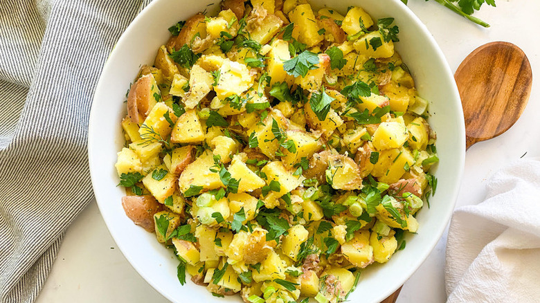 Herb-topped French potato salad in white bowl