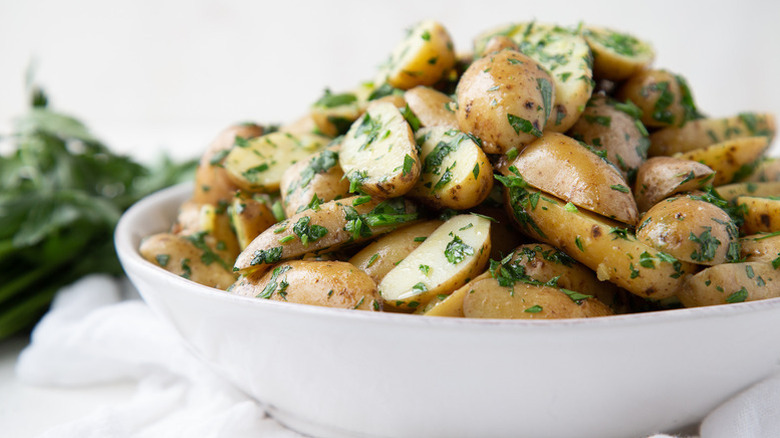 Pile of buttery herbed potatoes in white bowl