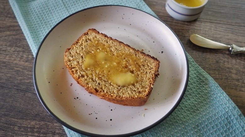 Slice of buttered banana bread on plate