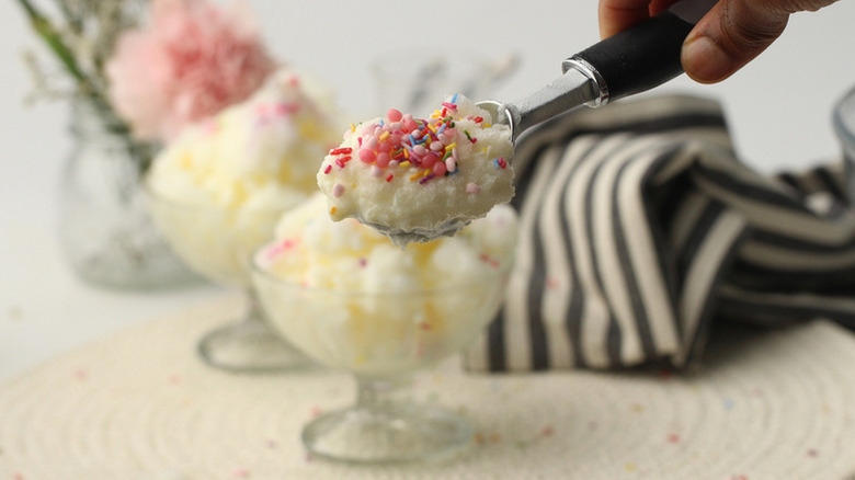 Scooping sprinkle-topped snow cream out of glass