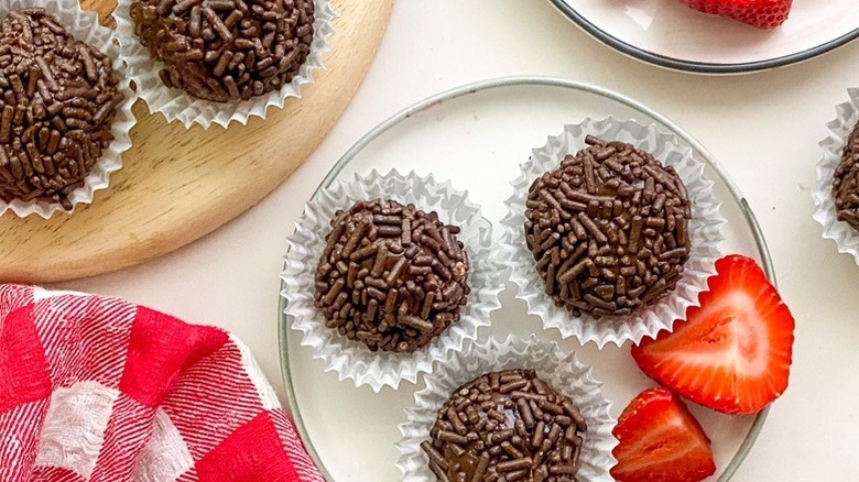 Chocolate Brigadeiros in white paper cases, served with strawberry slices