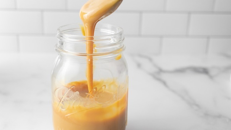 Spooning dulce de leche into glass jar