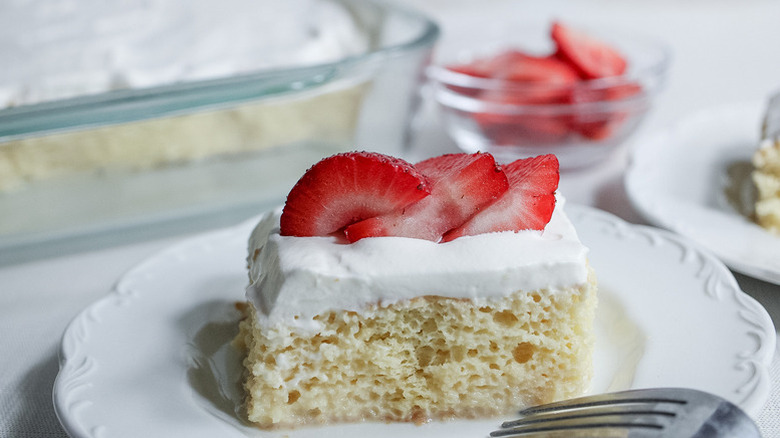 Slice of strawberry-topped tres leches cake on plate