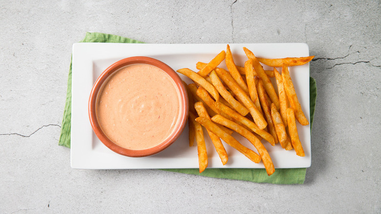 Bowl of chipotle mayo on white plate with pile of fries